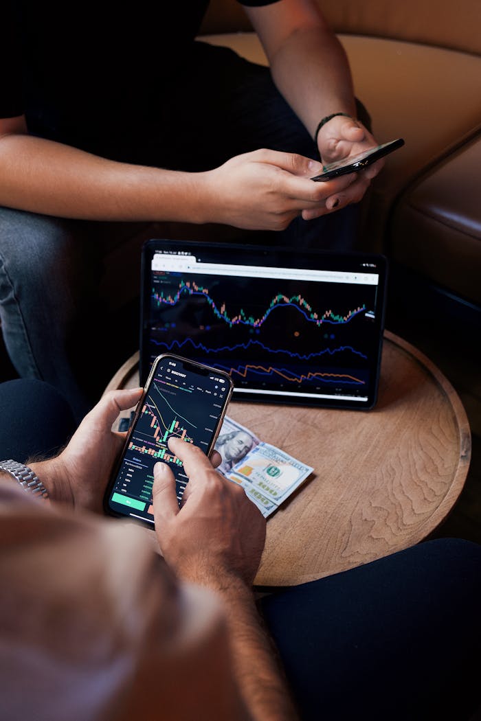 about-01 Two people using smartphone and tablet for trading stocks indoors.