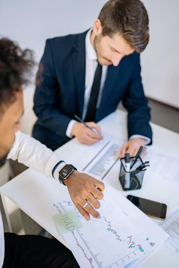 hero-img-01 Two businessmen analyzing stock charts and statistics during a meeting.